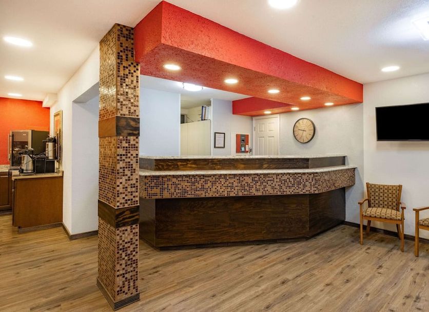 Travelodge by Wyndham Miles City lobby with front desk, wall clock, TV and seating area