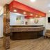 Travelodge by Wyndham Miles City lobby with front desk, wall clock, TV and seating area