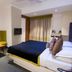 Sri Nanak Continental Hotel, New Delhi guest room with bed, sofa, TV, and window curtains