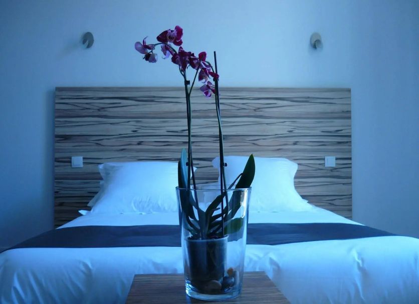 Hôtel En Ville in Aix-en-Provence bedroom with orchid vase on a bed and wood headboard