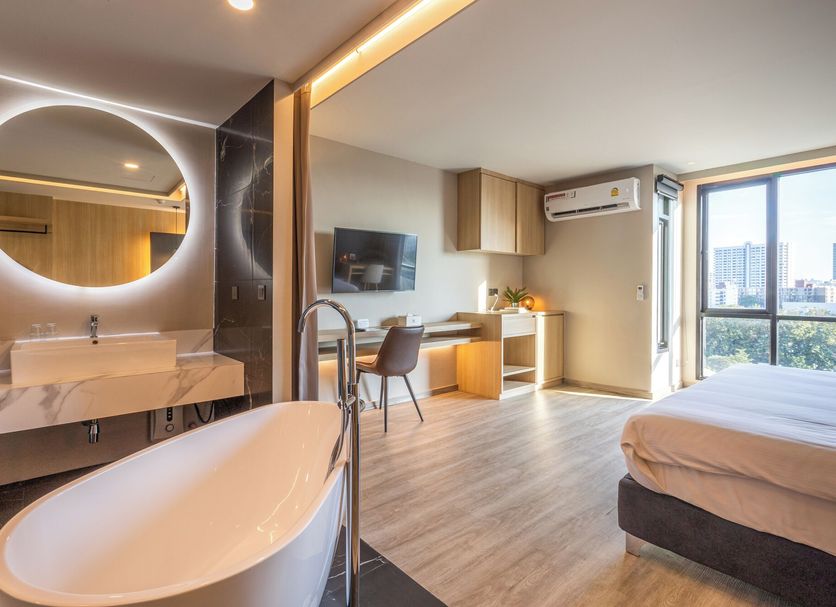 56 Hotel Bangkok room with freestanding tub, sink vanity, desk, bed and city view