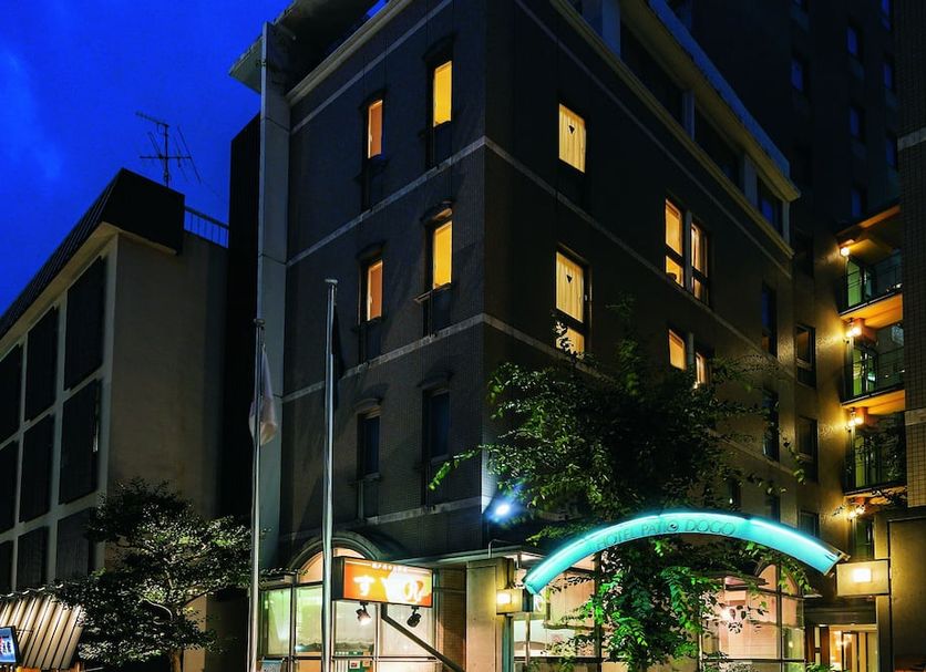 Hotel Patio Dogo in Matsuyama at night, exterior with lit windows and a glowing entrance arch