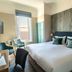 The Brudenell Aldeburgh guest room with king bed, bay window, and teal chairs in Ipswich