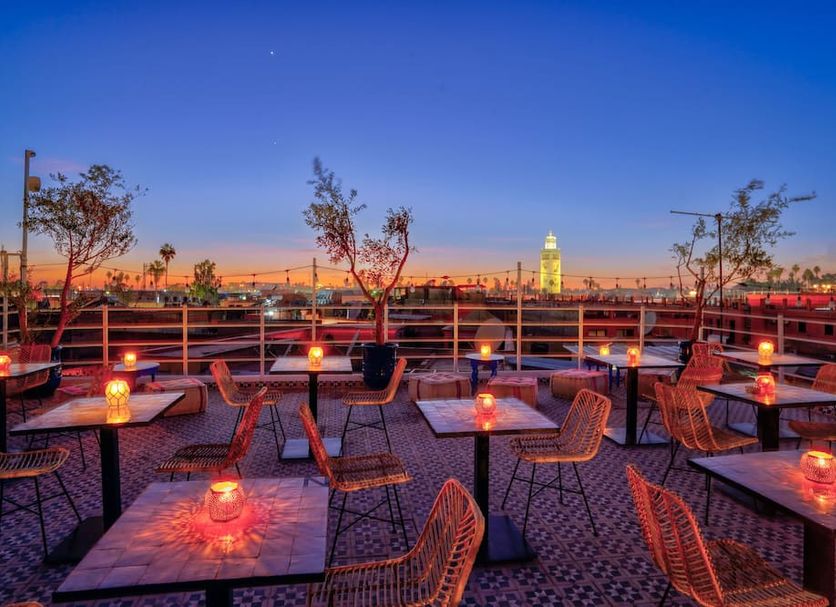 Riad Les Palmiers De La Medina rooftop terrace in Marrakech at sunset with lit tables and city views