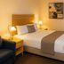 The Heritage Bendigo room in Bendigo with a neatly made bed, bedside lamps, armchair and wall art.