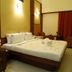 Fabhotel Prime Chennai Deluxe guest room with king bed, rose petals, and brown armchairs in Chennai.
