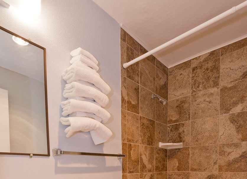 Riviera Inn Port Angeles bathroom with tub-shower combo, toilet, vanity and stacked towels