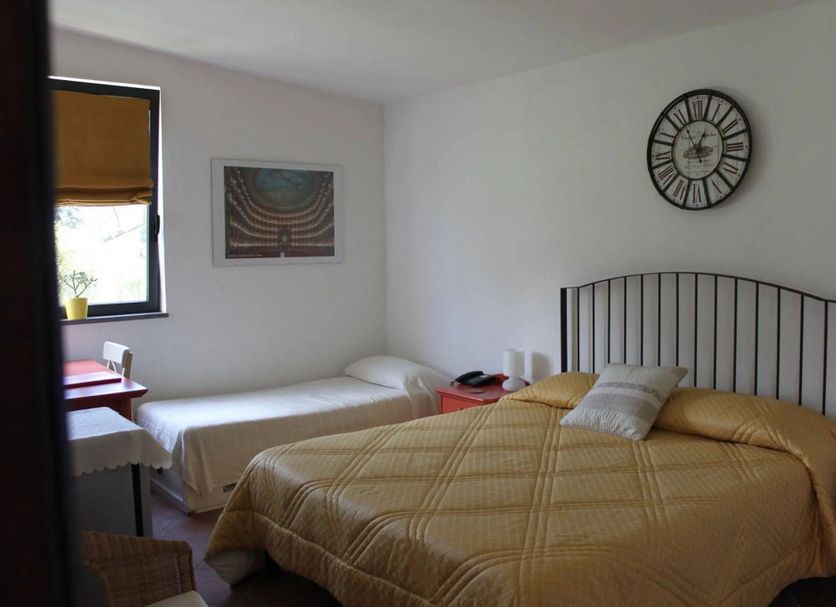 Flegrea House - Casa Rosa guest room in Pozzuoli with twin and double beds, wall clock, and window