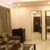 Hotel Sunny International in Mahabaleshwar room with sofa, wall-mounted TV, and mirrored doorway
