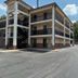 Motel 6 - Laurel, MS exterior with three-story building, parking lot, and fenced side driveway in Laurel