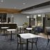Courtyard by Marriott Greensboro Airport lobby café with tables, chairs, and a coffee counter in Greensboro