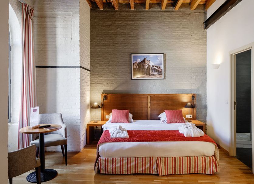 Ghent River Hotel in Ghent guest room with double bed, wooden headboard, and exposed beam ceiling