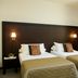 Sweet Hotel in Schiavon: twin beds with beige bedding, bedside lamps and tall curtains in a simple guest room