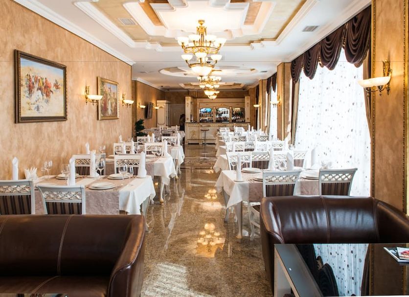 Boutique Hotel Buta Minsk elegant restaurant with set tables, chandeliers, and polished marble floor