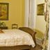 Dansereau House in Thibodaux: elegant guest room with canopy bed, antique furnishings and framed artwork