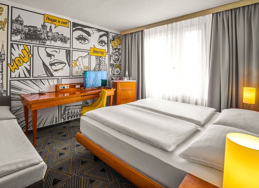 Hotel Uno Prague guest room with twin beds, desk, comic-style wall art, and bright window