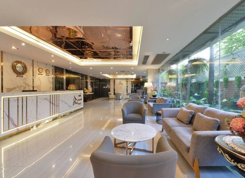Three Seasons Bangkok lobby lounge with seating, marble floors, and large garden-facing windows