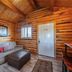 Zion Ponderosa Ranch Resort in Mount Carmel cabin interior with sofa, ottoman, wood walls, window and door