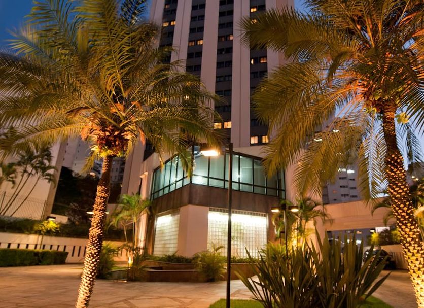 Ninety Hotel in Sao Paulo with palm trees and lit exterior at dusk