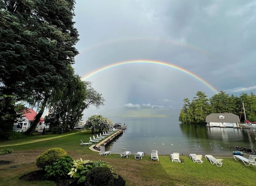 The Villas on Lake George in Diamond Point with lakeside dock, lounge chairs, and rainbow over the water