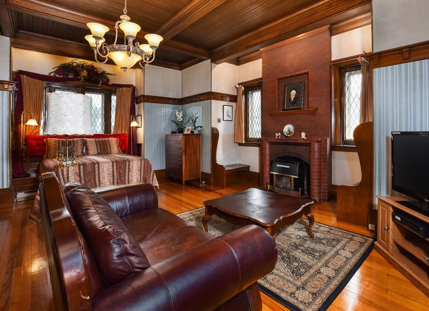 The Noble Suites in Brockville: vintage suite with leather sofa, fireplace, wood paneling and TV