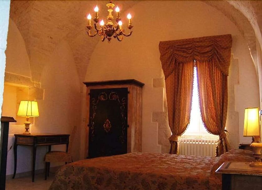 Masseria Magli Resort room in Martina Franca with arched ceiling, chandelier, and draped window