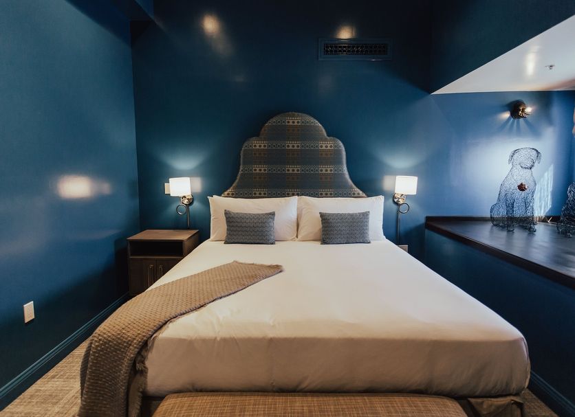 The Winston Solvang guest room with blue walls, king bed, and decorative headboard in Solvang.