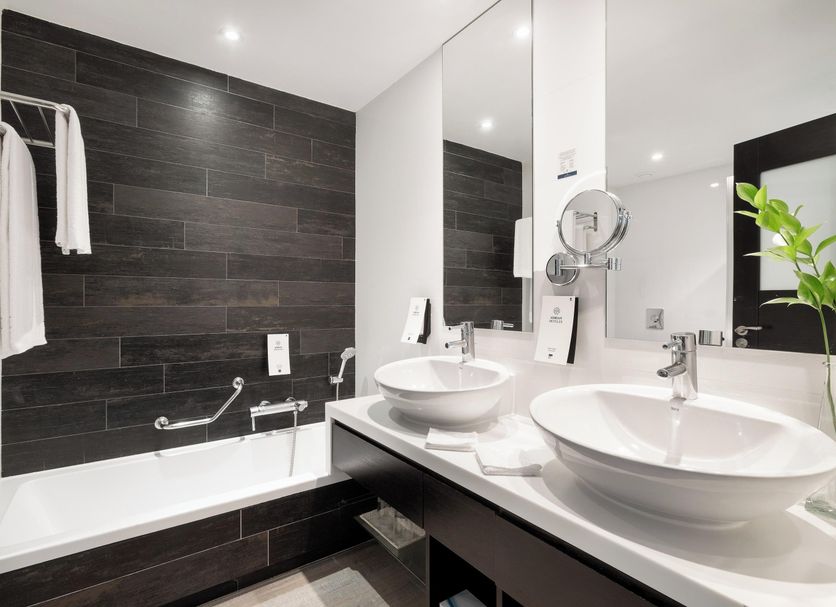 Adrian Hoteles Jardines De Nivaria bathroom with double sinks, bathtub and dark tile walls in Adeje