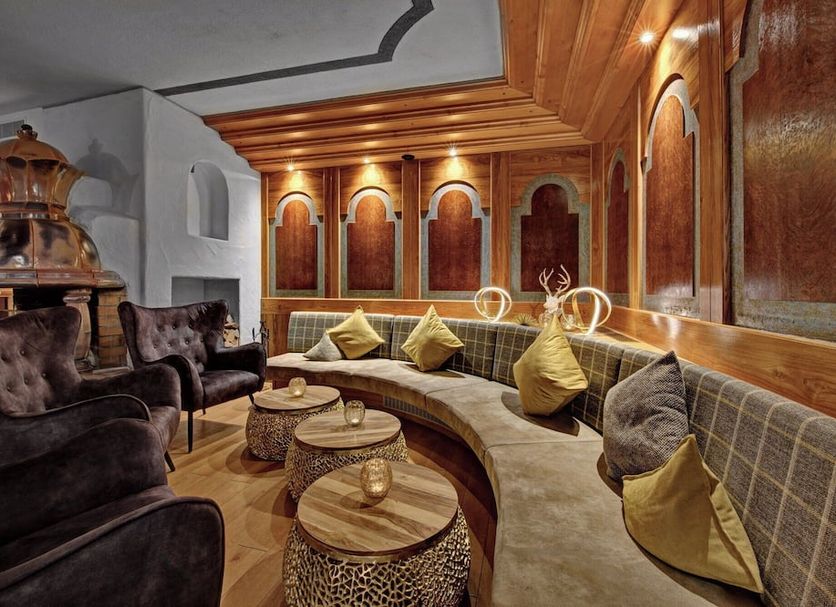 Königshof Hotel Resort in Oberstaufen lounge with curved seating, copper fire feature, and wood-paneled walls