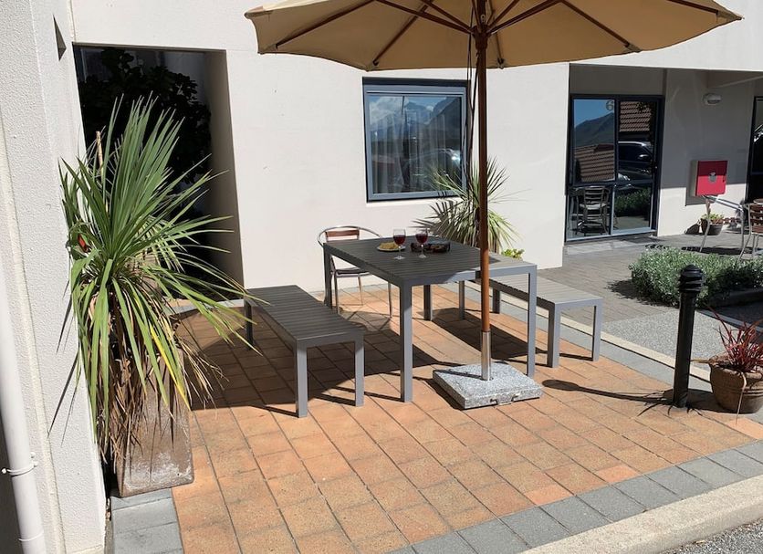Bella Vista Motel Wanaka outdoor patio with table, benches, umbrella and potted plants in Wanaka