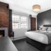 Qudos Salisbury hotel room with king bed, brick accent wall, fireplace and large window