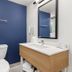 Spark by Hilton Harrisonburg University Area bathroom with blue accent wall, vanity, mirror, and toilet