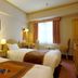 Hotel Monterey Nagasaki guest room in Nagasaki with two twin beds, desk, and window seating area