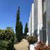 Kyriad Martigues Sud in Martigues: exterior walkway with cypress trees, shrubs and white building facade