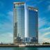 Onyx Rotana in Manama, twin glass towers rising above the waterfront under a blue sky