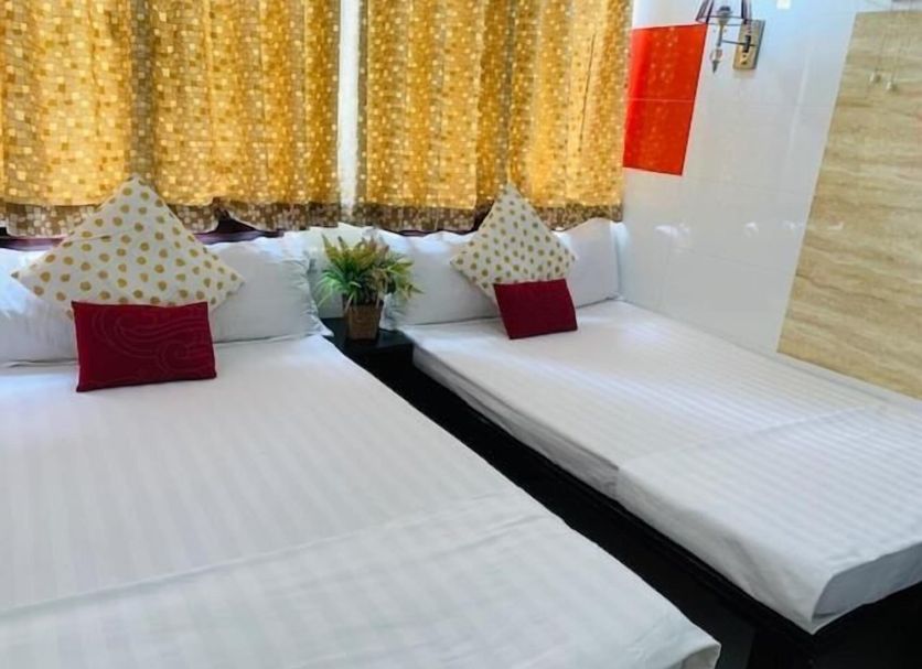 Woodstock Hostel Hong Kong twin room with white beds, patterned pillows and gold curtains