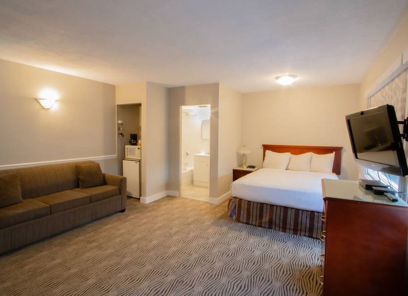 Scott's Inn & Suites in Kamloops guest room with sofa, bed, wall TV, and open bathroom doorway