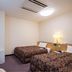 Hotel Ikedaya Matsumoto guest room with two beds, TV, and bedside lamp
