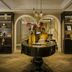 The Nikolai Hamburg lobby with round table, arched mirrors, shelves, and herringbone wood floor
