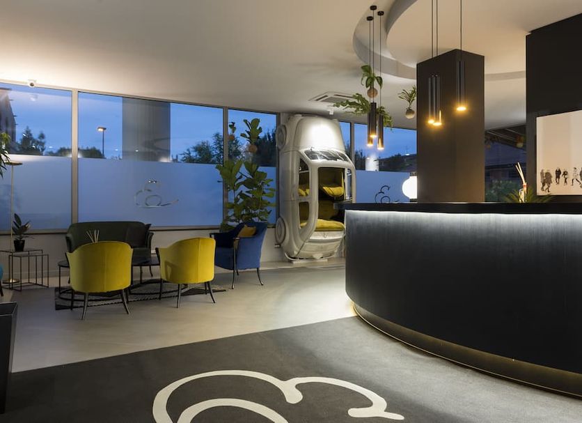 Elizabeth Lifestyle Hotel in Bologna lobby with curved reception desk, lounge chairs, and hanging lights