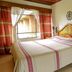 Hotel Pie de la Sierra in Uruapan: guest room with wooden bed, striped bedspread, window and bedside table.