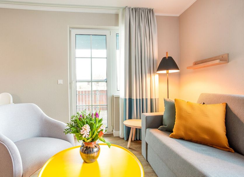 Beech Resort Fleesensee room in Goehren-Lebbin with sofa, armchair, balcony door and flowers