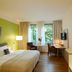Flottwell Berlin Hotel guest room with bed, desk, chairs, and large windows in Berlin