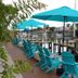 Latitude 26 Waterfront Boutique Resort - Fort Myers Beach patio with turquoise chairs and umbrellas by the water