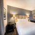 Sonesta Simply Suites Pittsburgh Airport guest room with king bed, bedside lamps, and desk