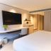 The Bauhinia Hotel - Central guest room with king bed, wall-mounted TV, and desk in Hong Kong