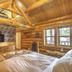 Hibernation Station in West Yellowstone log cabin guest room with TV, stone fireplace, and wood-beam ceiling
