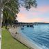 Montpellier Boutique Resort in Noosaville with a waterfront lawn, beach, and sailboats at sunset