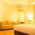 Horison Hotel Sukabumi guest room with bed, sofa, mirror and warm lighting