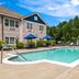 The Hotel Saratoga in Saratoga Springs features an outdoor pool beside a beige guest building and lounge chairs.